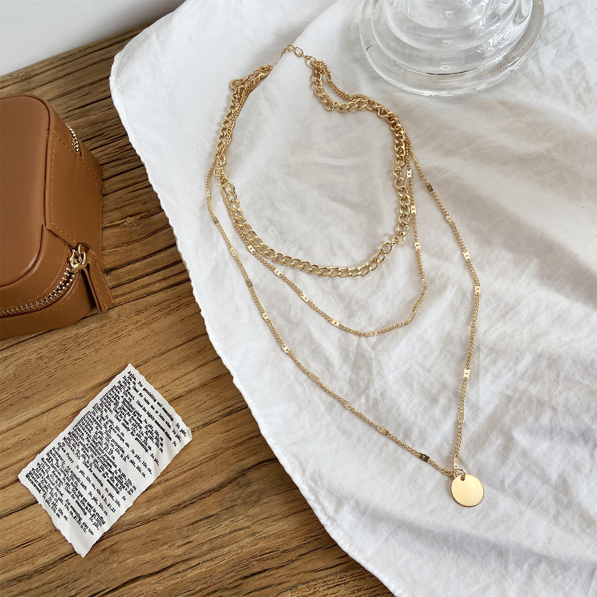 Women’s layered necklace featuring delicate chain links and minimalist disc charms.